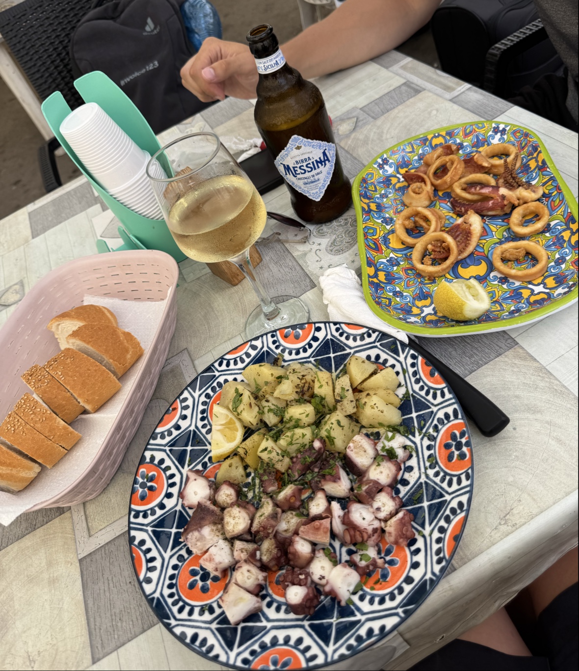 Polpo e calamari fritti nei piatti di ceramica siciliana, con pane e Birra Messina